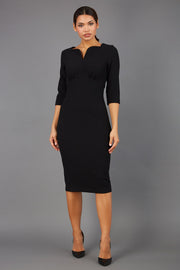 Brunette model wearing Diva Catwalk Lovell Pencil Dress in black  with lowered sweetheart neckline and three quarter sleeve with gathering at the bust front
