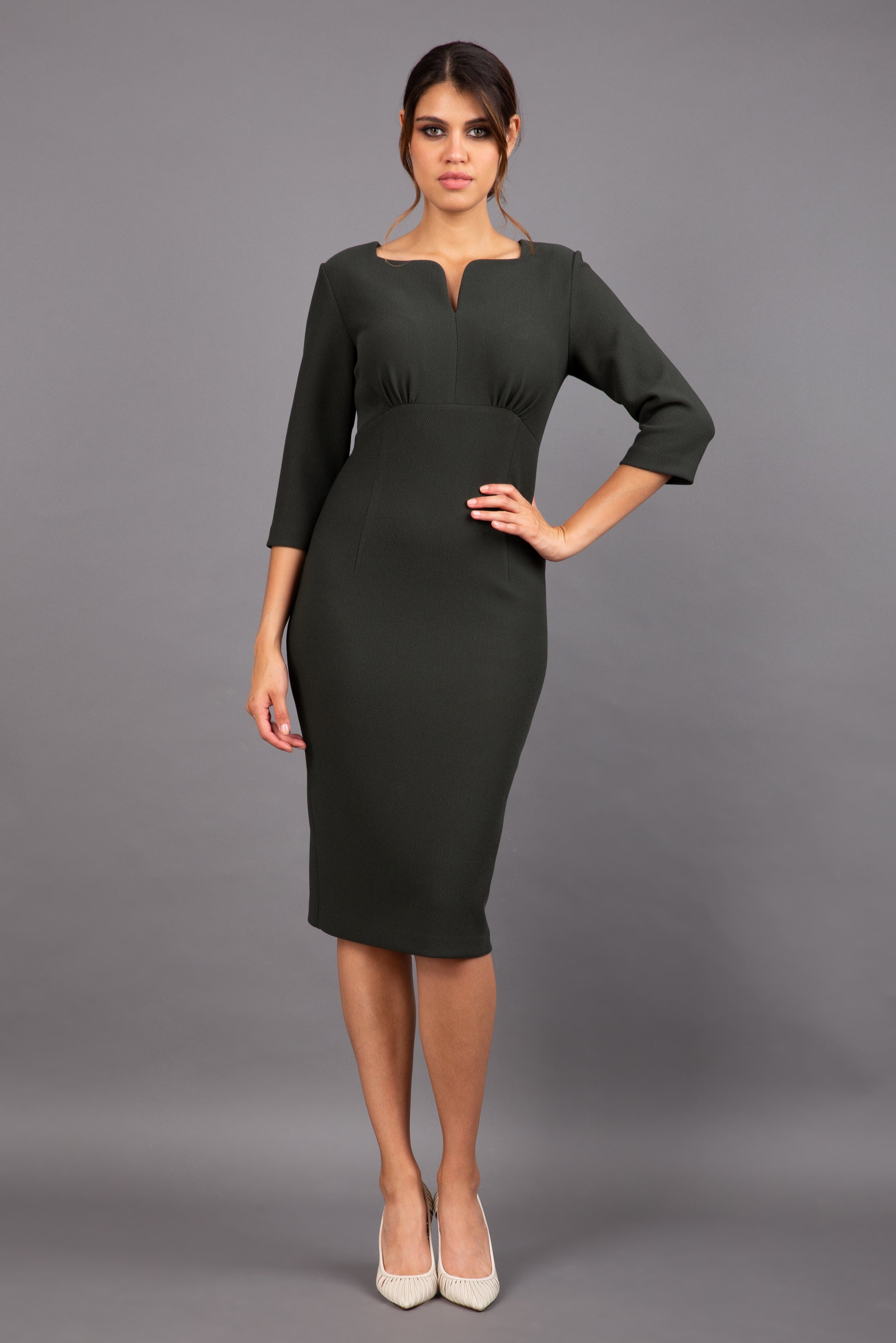 Brunette model wearing Diva Catwalk Lovell Pencil Dress in Obsidian Green with lowered sweetheart neckline and three quarter sleeve with gathering at the bust front