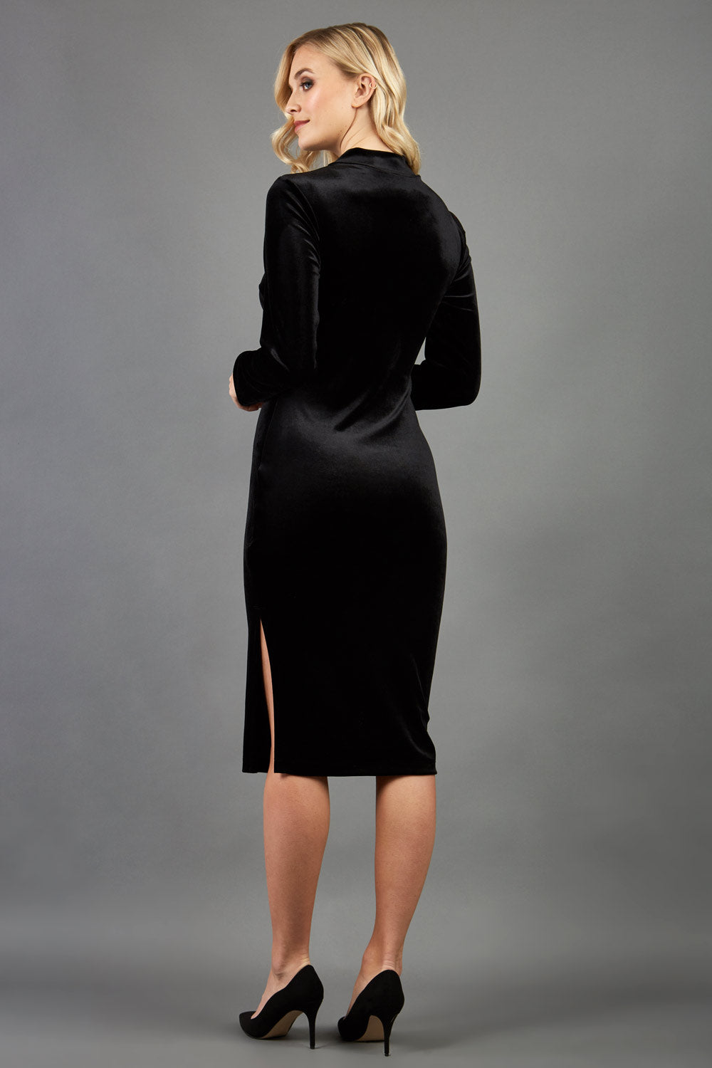brunette model wearing diva catwalk clipper pencil skirt dress velvet sleeved style with a keyhole detail and high neck and split on a side of the skirt in colour black back
