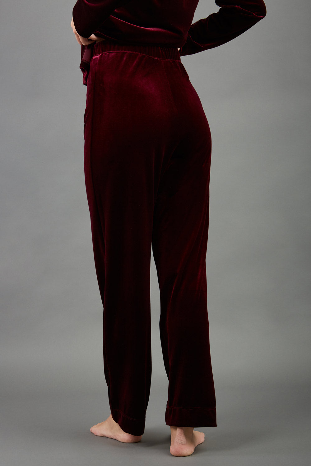 model wearing diva catwalk pelham stretch velvet straight leg trousers in velvet with ribbon in burgundy colour back