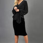 Blonde hair model is wearing a jersey sparkle v neck wrap blouse with bishop sleeve detail and bow on a side front image