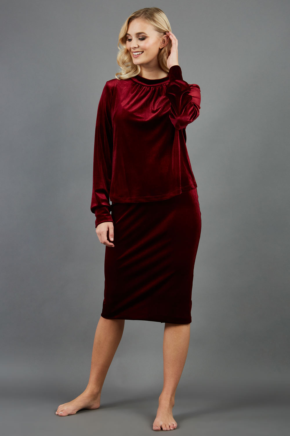 model is wearing diva catwalk triste velvet pencil skirt in burgundy front paired with diva long sleeve allium top