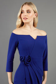 blonde model is wearing diva catwalk charisma dress odd shoulder design with pleated detail down the front and flower detail on a side in navy blue front