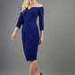blonde model is wearing diva catwalk charisma dress odd shoulder design with pleated detail down the front and flower detail on a side in navy blue front