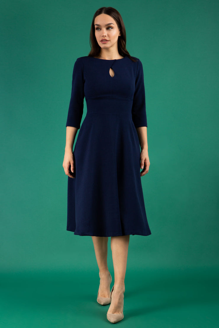Brunette model is wearing diva catwalk casares swing dress with a keyhole neckline three quarter sleeve dress with pocket detail in navy blue front