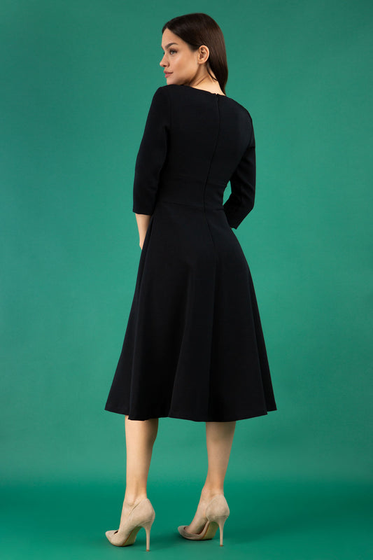 Brunette model is wearing diva catwalk casares swing dress with a keyhole neckline three quarter sleeve dress with pocket detail in black back
