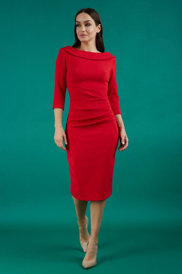 A brunette model is wearing a round neckline pencil dress with pleating on the tummy area in red front image