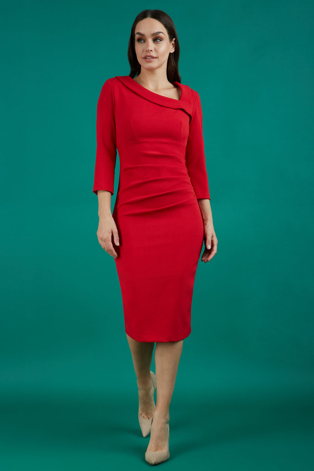 Brunette model is wearing a red pencil three quarter sleeve dress with assymetric neckline and pleating around tummy area