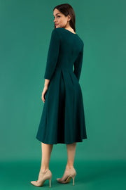A brunette model is wearing a split neckline sleeved swing Aline dress from Diva Catwalk in forest green
