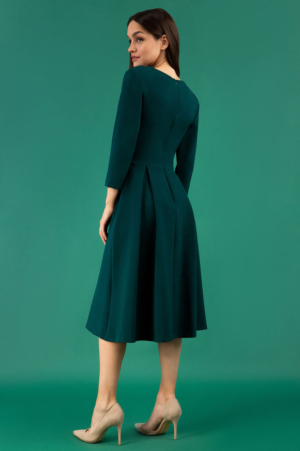 A brunette model is wearing a split neckline sleeved swing Aline dress from Diva Catwalk in forest green