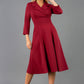 A blonde model is wearing a swing wine three quarter sleeve dress with oversized collar and pockets in the skirt  