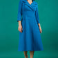 A brunette model is wearing a swing teal three quarter sleeve dress with oversized collar and pockets in the skirt