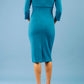 model is wearing diva catwalk chandos sheath dress with three quarter sleeve and slit in the middle of the neckline in teal back