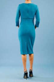 model is wearing diva catwalk chandos sheath dress with three quarter sleeve and slit in the middle of the neckline in teal back
