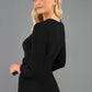 A blonde Model is wearing a cut out peep hole neckline pencil dress with pleating across the tummy area and 3/4 sleeve lenght sleeve in black back image