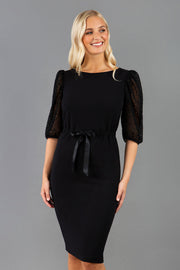 Blonde model is wearing Diva Catwalk Zermatt Lace Short Sleeved Black Pencil skirt Dress with a Belt Detail at the front good for corporate  events and as an office dress or workwear style