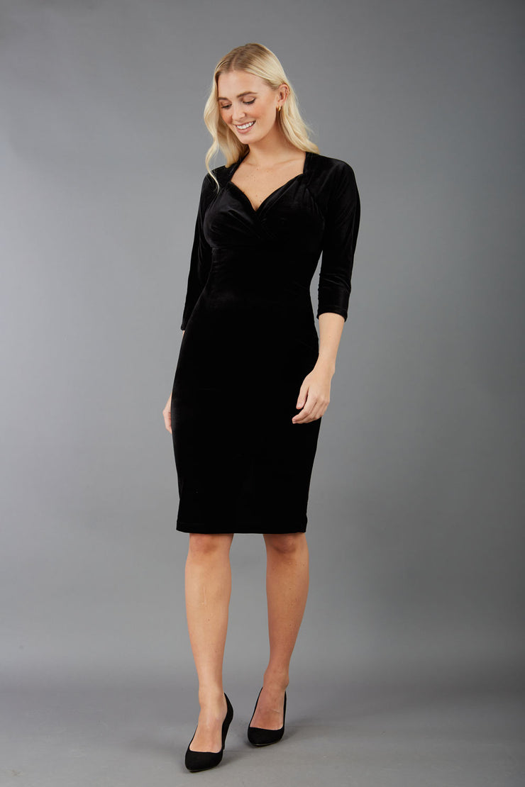 A blonde model is wearing a velvet pencil sweetheart neckline dress by diva catwalk in black