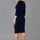 A blonde model is wearing a 3/4 sleeve pencil dress with the keyhole details in navy