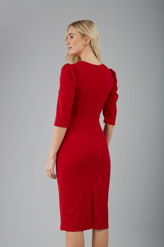 blonde model is wearing diva catwalk lucretis rounded neckline sleeved pencil dress with  rushing on shoulders and rushed detail on a side of a waistline in red back