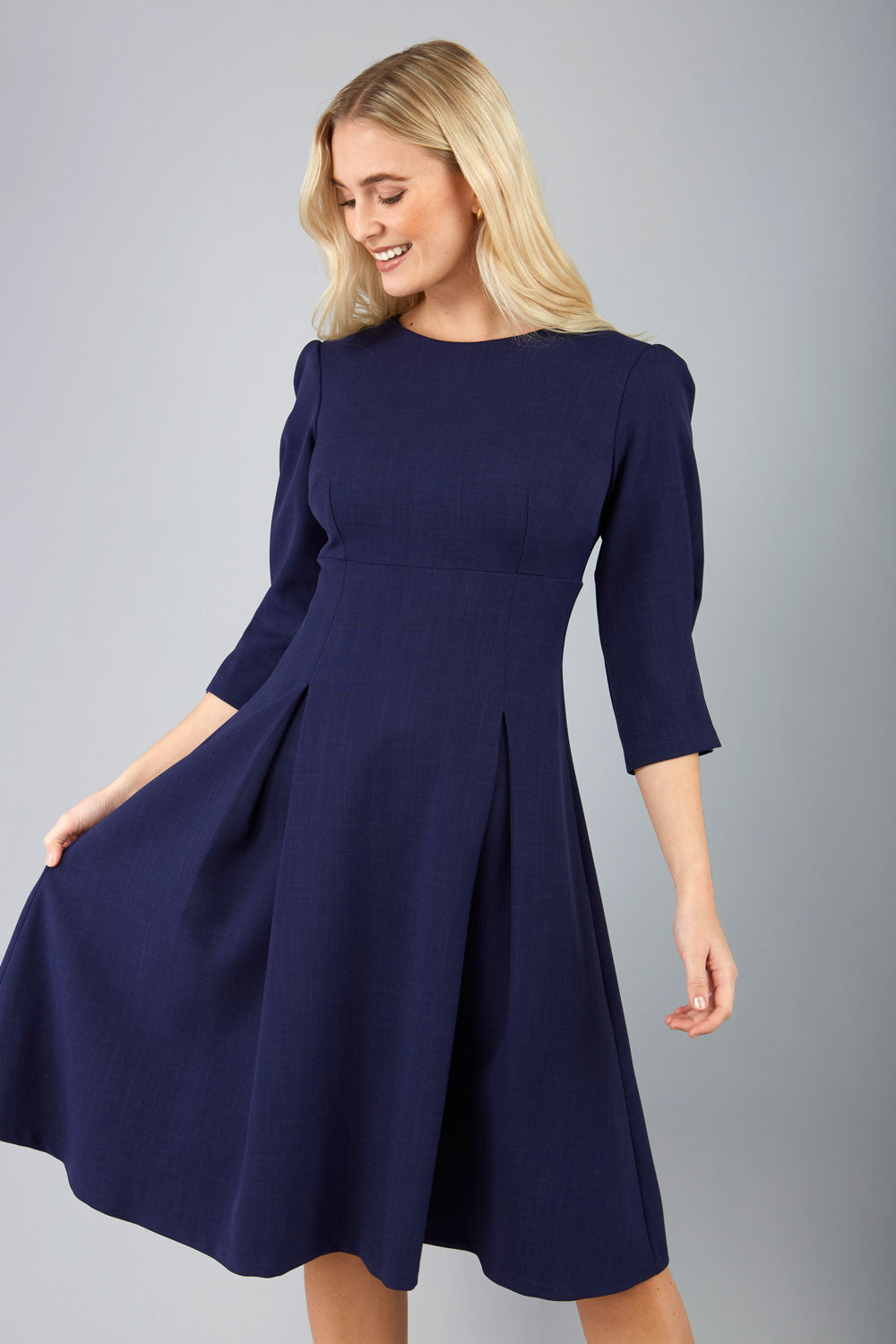 blonde model is wearing diva catwalk harpsden a-line skirt 3/4 sleeve swing dress with rounded neckline in navy blue front