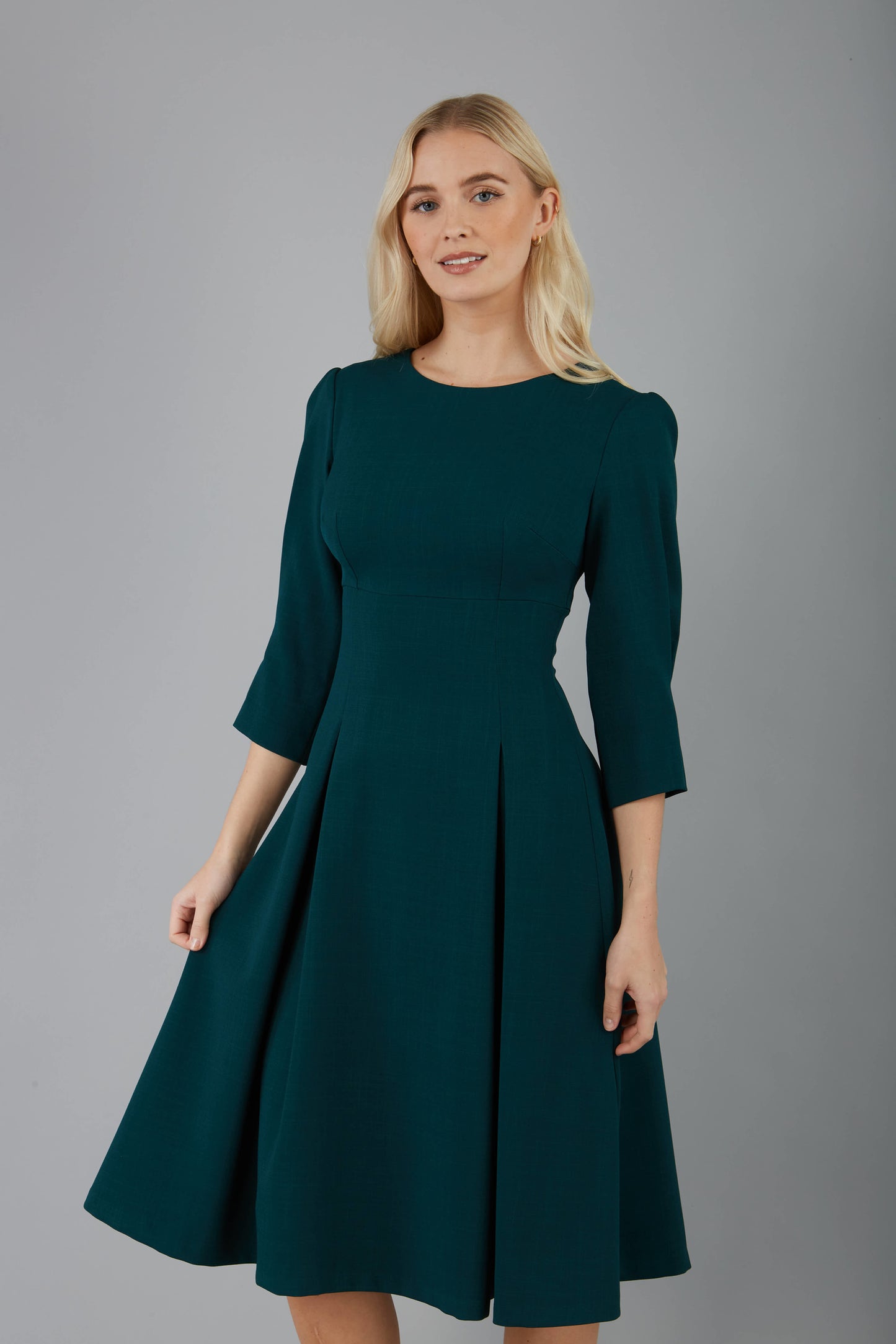 blonde model is wearing diva catwalk harpsden a-line skirt 3/4 sleeve swing dress with rounded neckline in forest green front