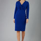 blonde model is wearing diva catwalk gately pencil dress with long sleeves and twisted low v-neck in royal blue front