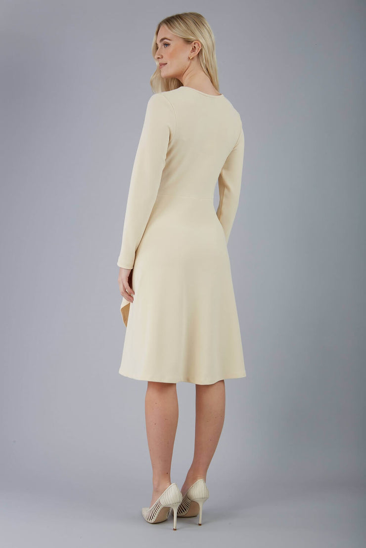 blonde model is wearing diva catwalk moraig swing long sleeve dress with high cowl neckline and wrap skirt in beige back