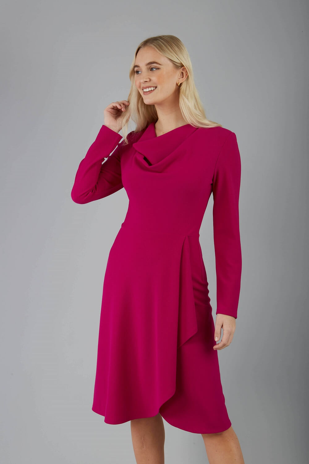 blonde model is wearing diva catwalk moraig swing long sleeve dress with high cowl neckline and wrap skirt in magenta front