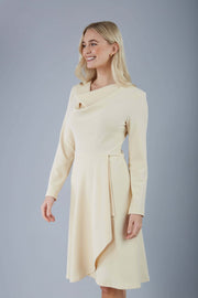 blonde model is wearing diva catwalk moraig swing long sleeve dress with high cowl neckline and wrap skirt in beige front
