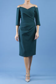 model is wearing diva catwalk lauren odd shoulder asymmetric neckline pencil dress with sleeves in forest green front