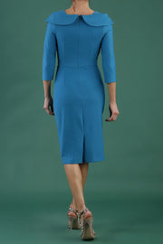 brunette model is wearing diva catwalk pencil dress with collar and a button detail on a side with 3/4 sleeve in mosaic blue back