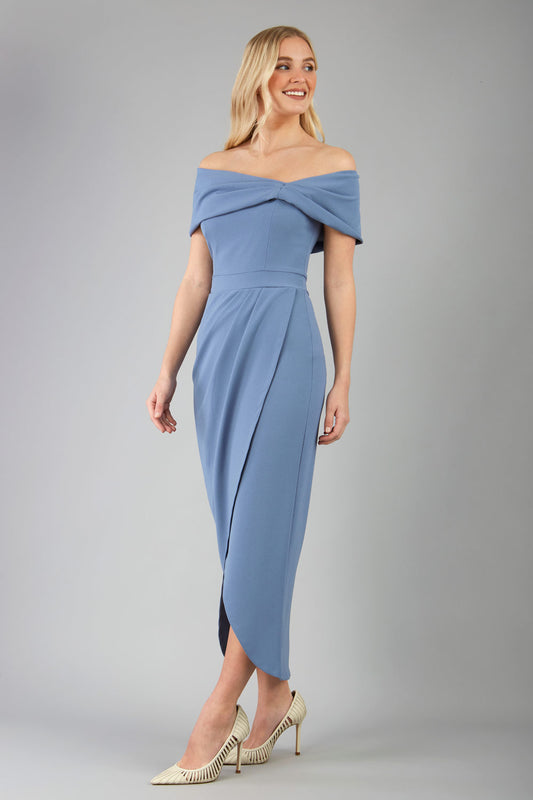 odel wearing diva catwalk vegas calf length stone blue midaxi dress with wide bardot neckline and open shoulders with a large opening at the front of the skirt with pleating coming down long skirt front 