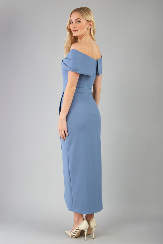 odel wearing diva catwalk vegas calf length stone blue midaxi dress with wide bardot neckline and open shoulders with a large opening at the front of the skirt with pleating coming down long skirt back