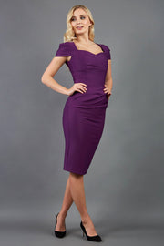 blonde model is wearing diva catwalk seed bonnie pencil skirt dress with cap sleeves and sweetheart neckline with pleating across the tummy in colour purple front