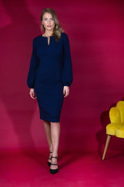 Blonde model wearing Diva Catwalk Praktica long puffed bishop sleeves knee length empire line pencil dress with round neckline with a slit cut in the middle in Navy Blue front
