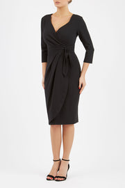 model wearing diva catwalk elan elegant black dress with 3 4 sleeves with a tie detail and asymmetrical closing front