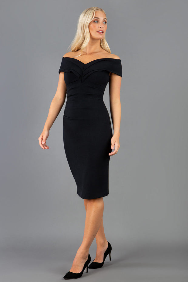 Model is wearing an off shoulder pencil dress by Diva Catwalk in black