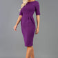 Blonde model is wearing a sleeved pencil dress with round neckline in purple with pockets in the skirt front image