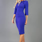 A model is wearing a three quarter sleeve pencil dress with a round neckline and bow detail at the front in spectrum indigo.