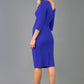 A model is wearing a three quarter sleeve pencil dress with a round neckline and bow detail at the front in spectrum indigo. back image