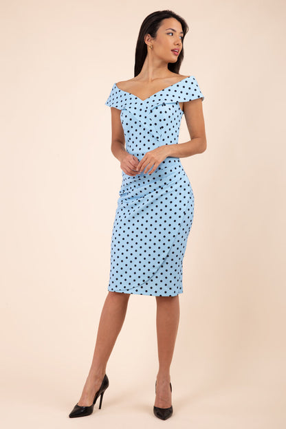 Brunette model wearing Diva Catwalk Fenella Polka Dot Pencil Sleeveless Dress off shoulder bardot neckline in blue front