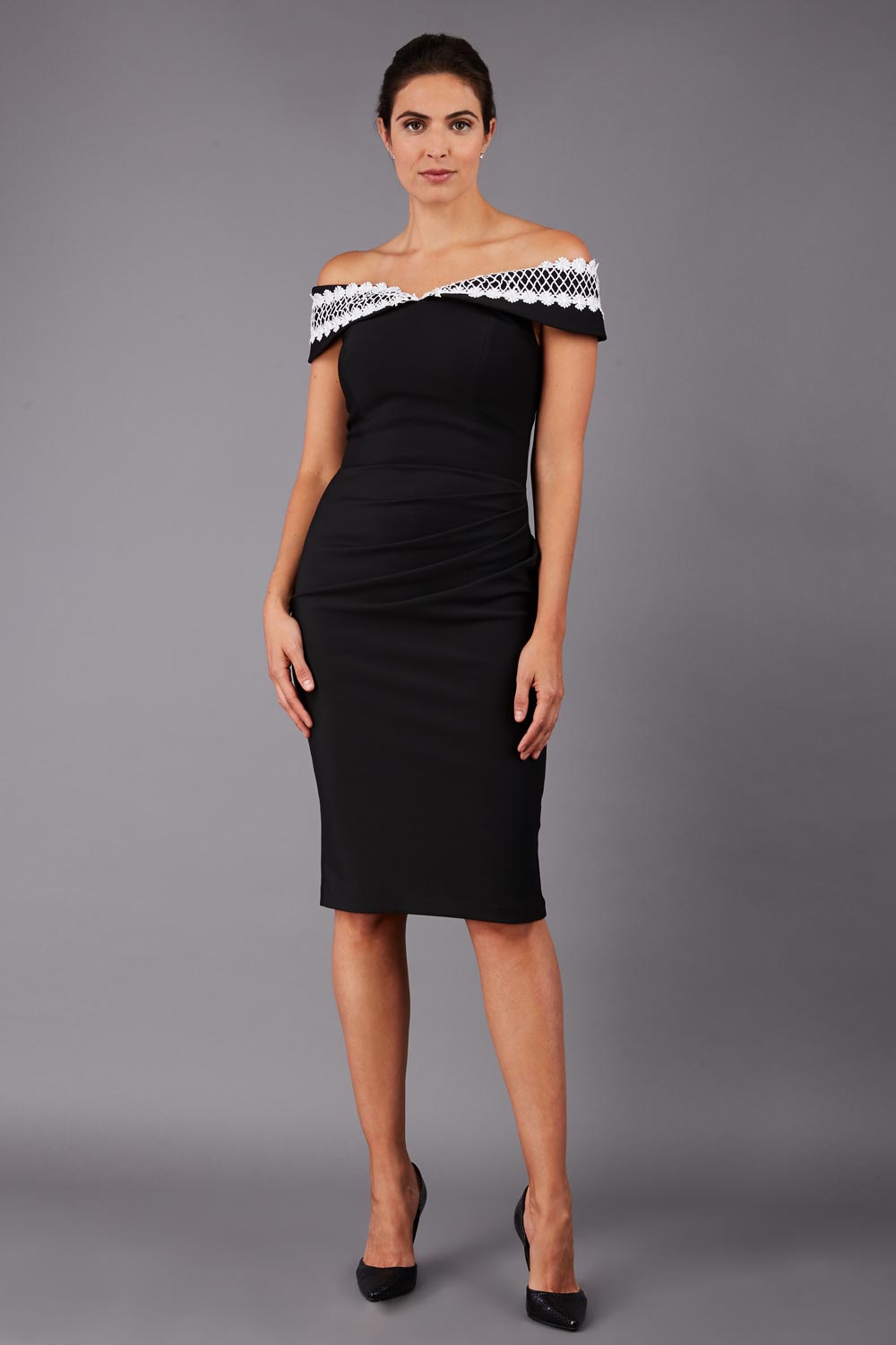 brunette model wearing diva catwalk kurumba pencil dress with bardot off shoulder neckline and lace detail across it in black and white colour front