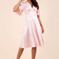 brunette model wearing diva catwalk cambrian satin swing dress with bell short sleeve wide asymmetric waistband and pleating under bust in pink front