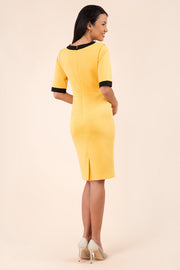 brunette model wearing Diva catwalk goggle pencil dress with short sleeve and v-neckline with contrasted design across body in yellow back
