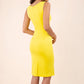 blonde model wearing diva catwalk plain pencil sleeveless dress in blazing yellow back