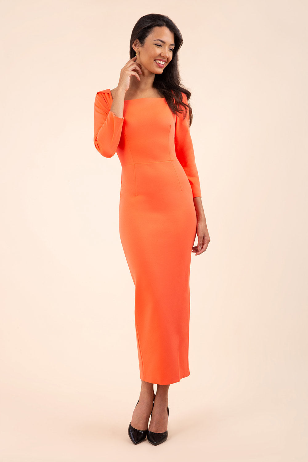 brunette model wearing diva catwalk maxi plain three quarter sleeve dress with pleating on shoulders and square neckline in hot coral front