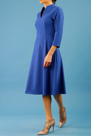 model is wearing diva catwalk palmerston vintage style a-line dress with sleeves and high neck with a slit in monaco blue colour front