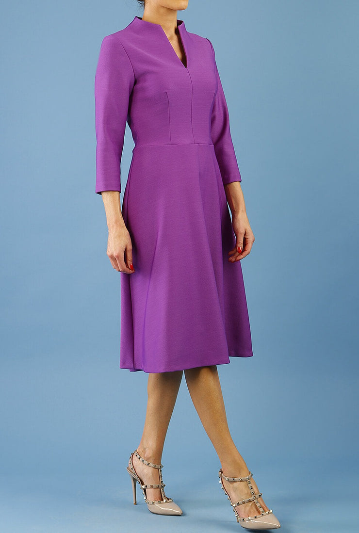 model is wearing diva catwalk palmerston vintage style a-line dress with sleeves and high neck with a slit in amethyst purple colour front