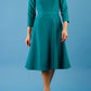 model is wearing diva catwalk palmerston vintage style a-line dress with sleeves and high neck with a slit in pacific green colour front