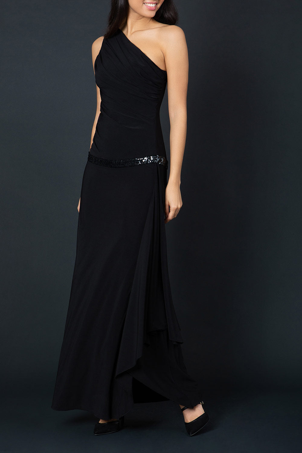Model wearing Temptress Full length Sleeveless Asymmetric One shoulder A-line Swing dress with sparkling band detail across the waist area in black front